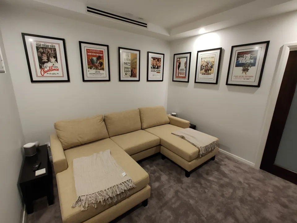 Movie posters in black frames with white mats displayed above a sofa in a customer's media room.